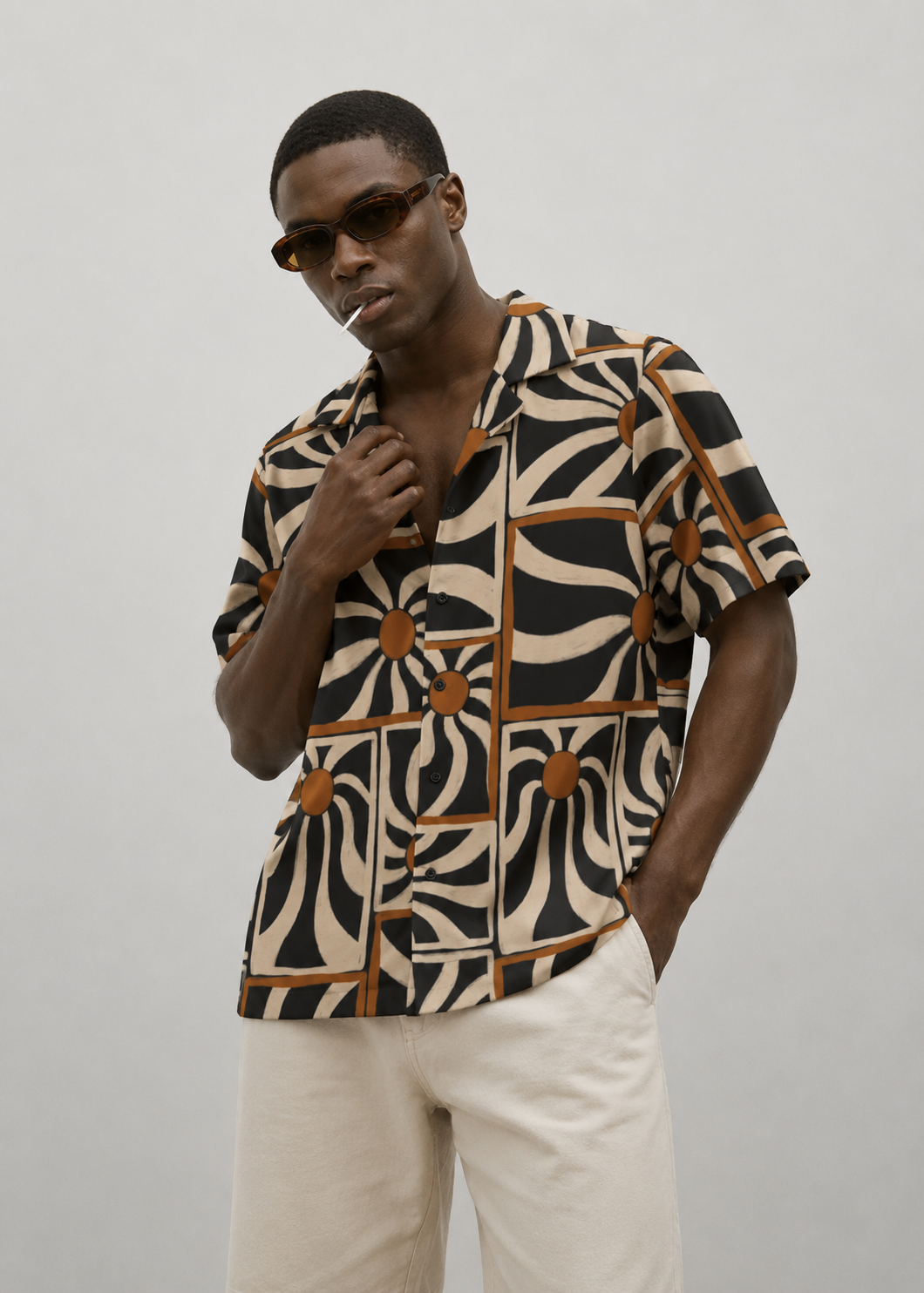Man wearing a patterned shirt and sunglasses against a plain background