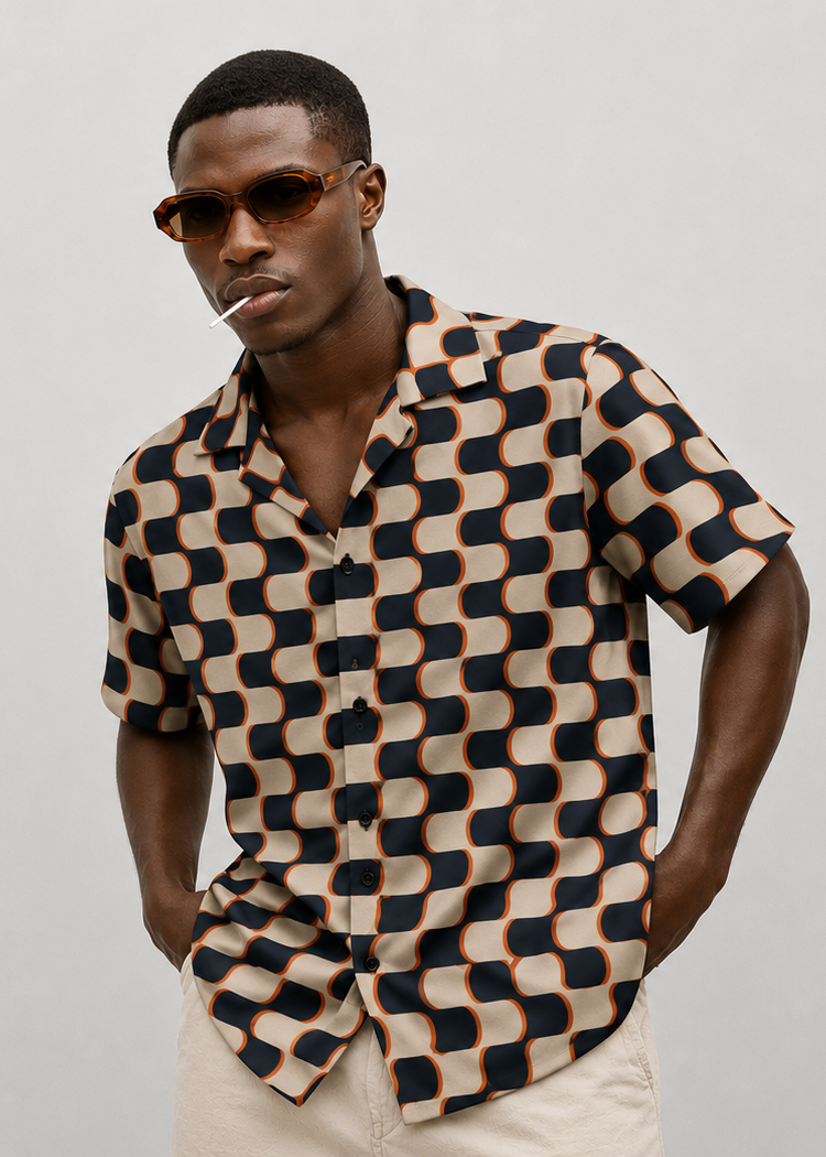 Man wearing a patterned shirt and sunglasses against a plain background