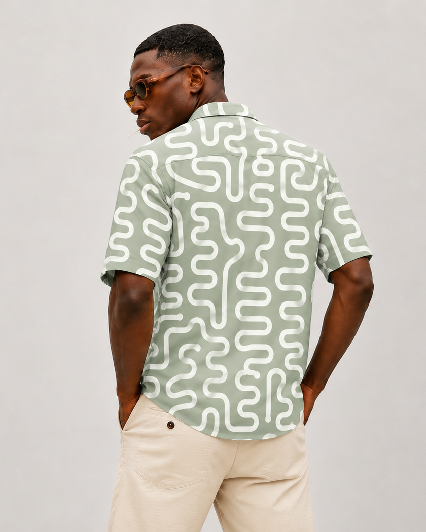 Man wearing a patterned shirt and beige pants on a plain background