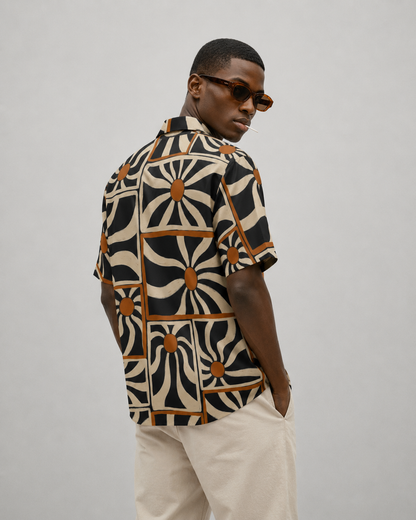 Man wearing a patterned shirt and sunglasses on a plain background