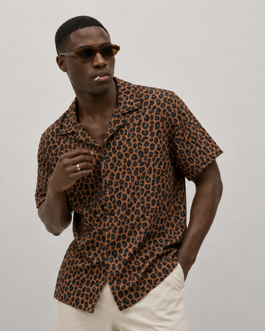 Man wearing a leopard print shirt and sunglasses on a plain background