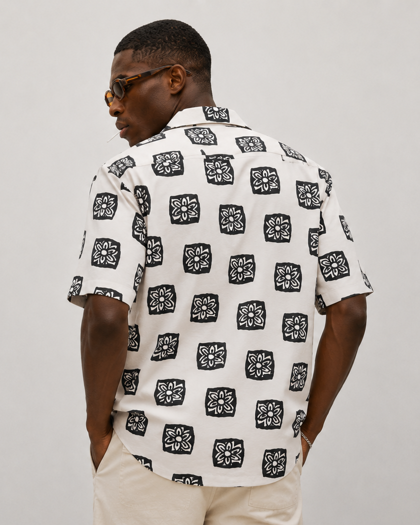 Man wearing a white shirt with black pattern on a gray background