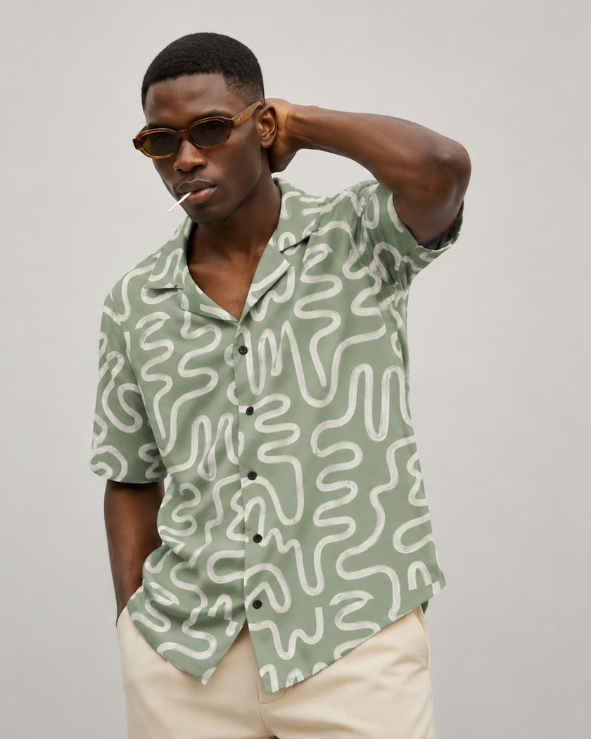 Man wearing a green patterned shirt and sunglasses against a plain background