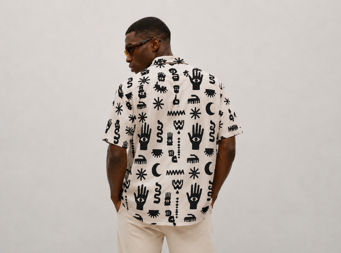 Man wearing a white shirt with black geometric pattern against a plain background
