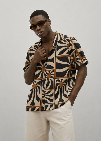 Man wearing a patterned shirt and sunglasses against a plain background