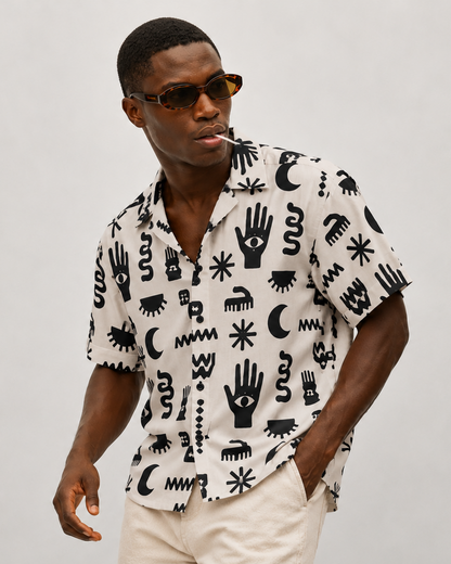 Man wearing a patterned shirt and sunglasses against a plain background
