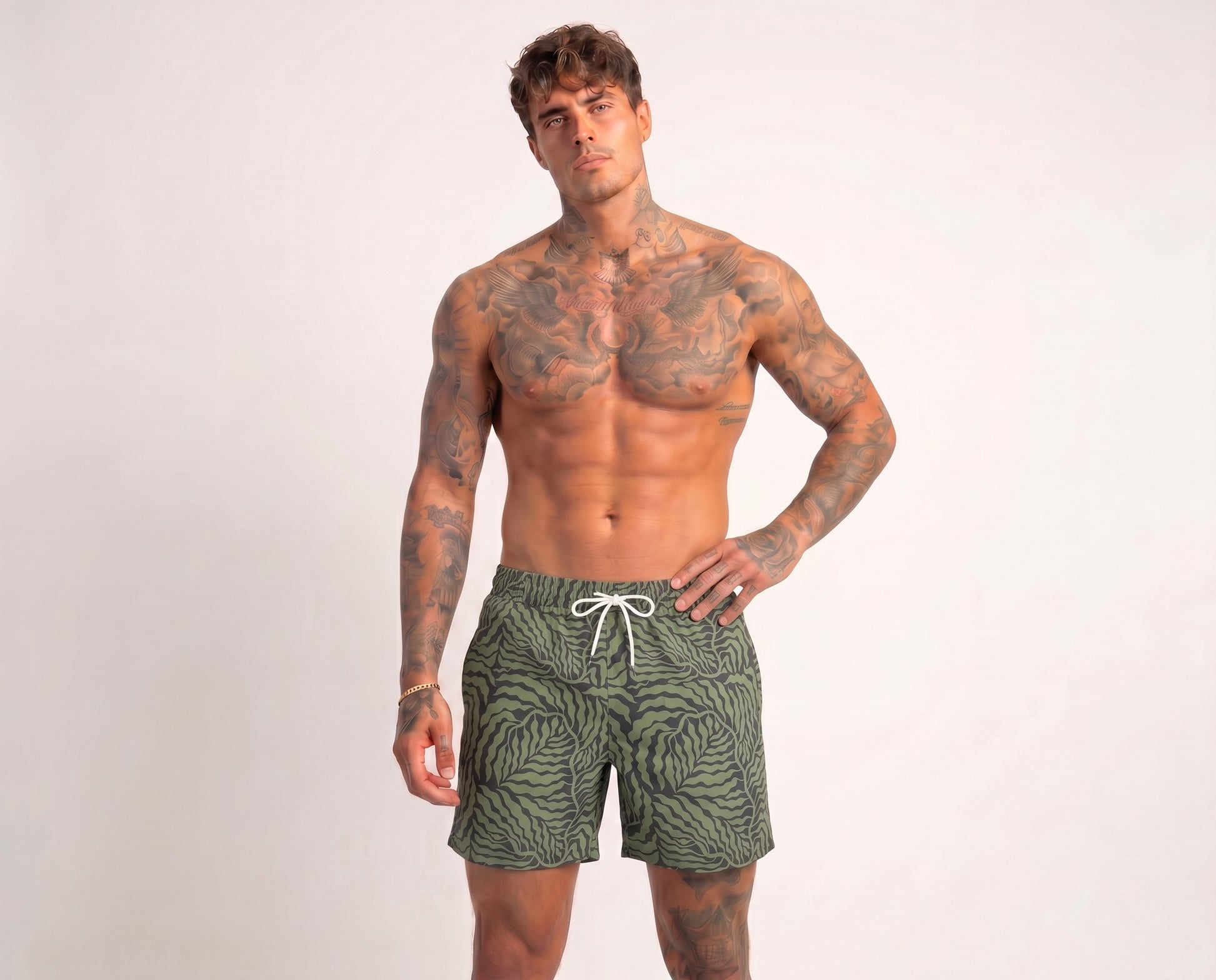 Man wearing green patterned swim shorts on a white background