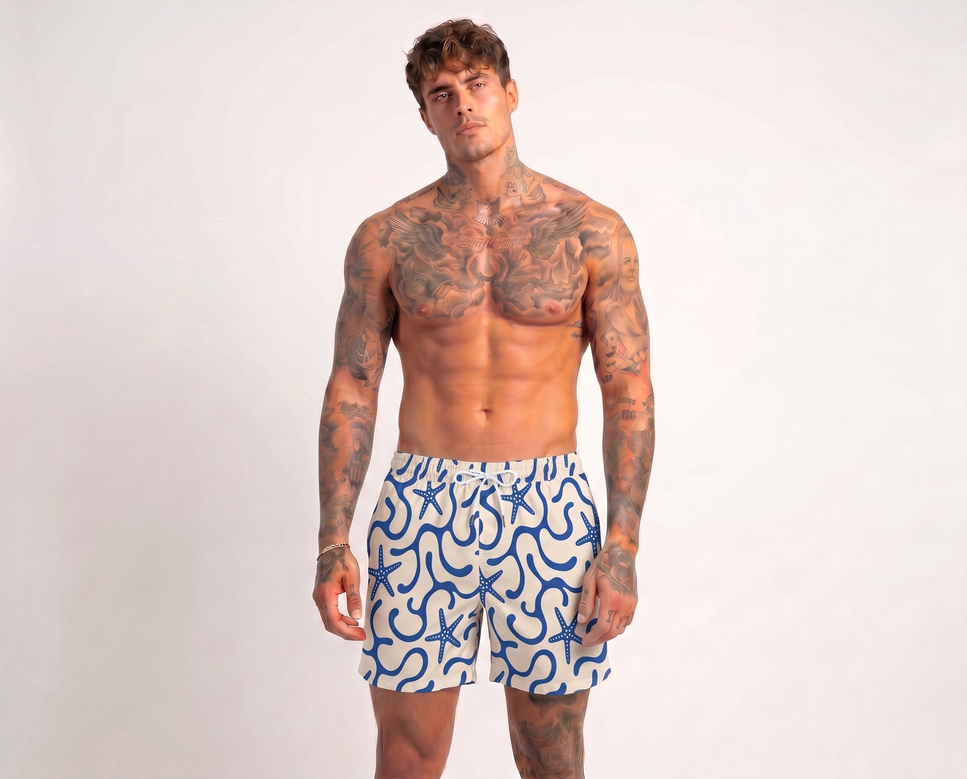 Man wearing blue and white patterned swim shorts on a plain background