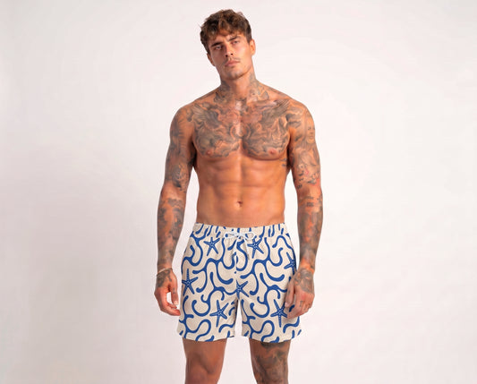 Man wearing blue and white patterned swim shorts on a plain background
