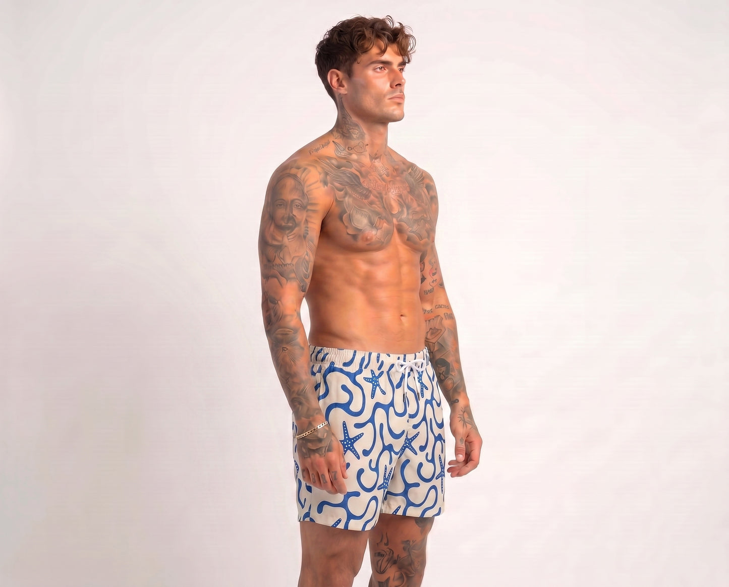 Man wearing blue and white patterned swim shorts on a plain background