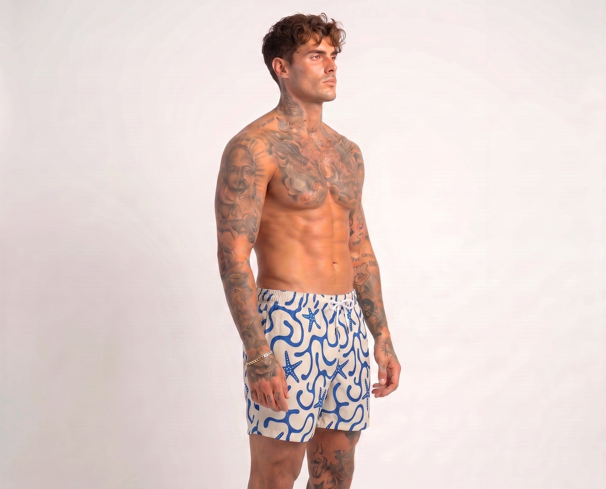Man wearing blue and white patterned swim shorts on a plain background