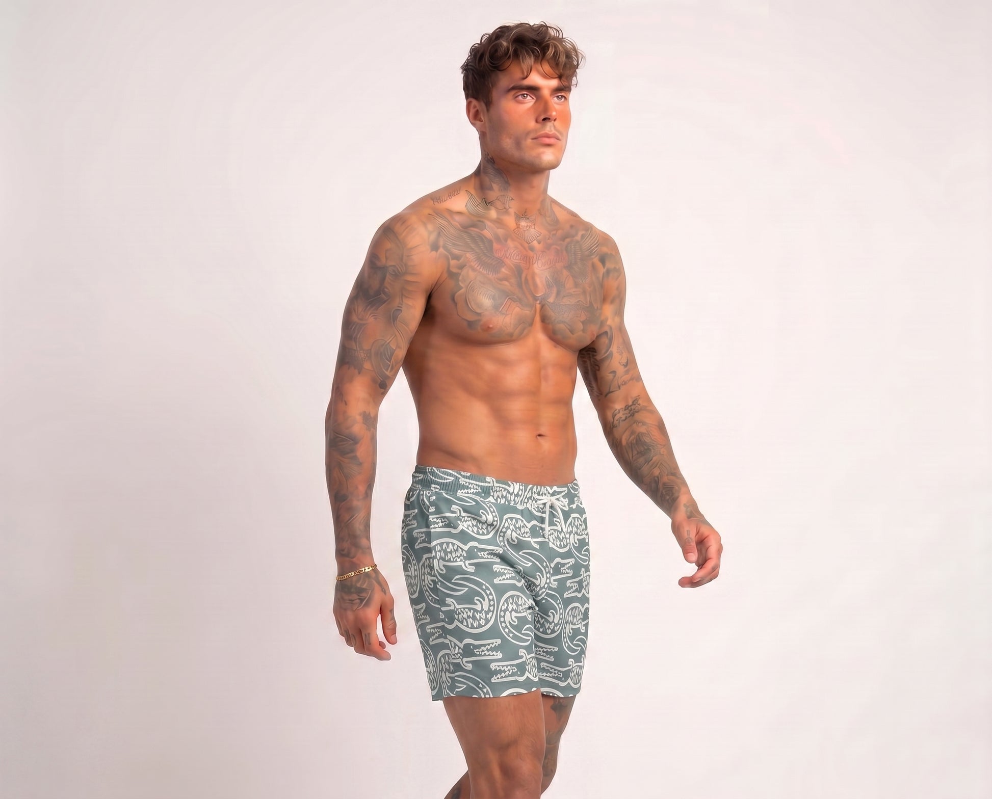 Man wearing green swim shorts with a pattern on a white background