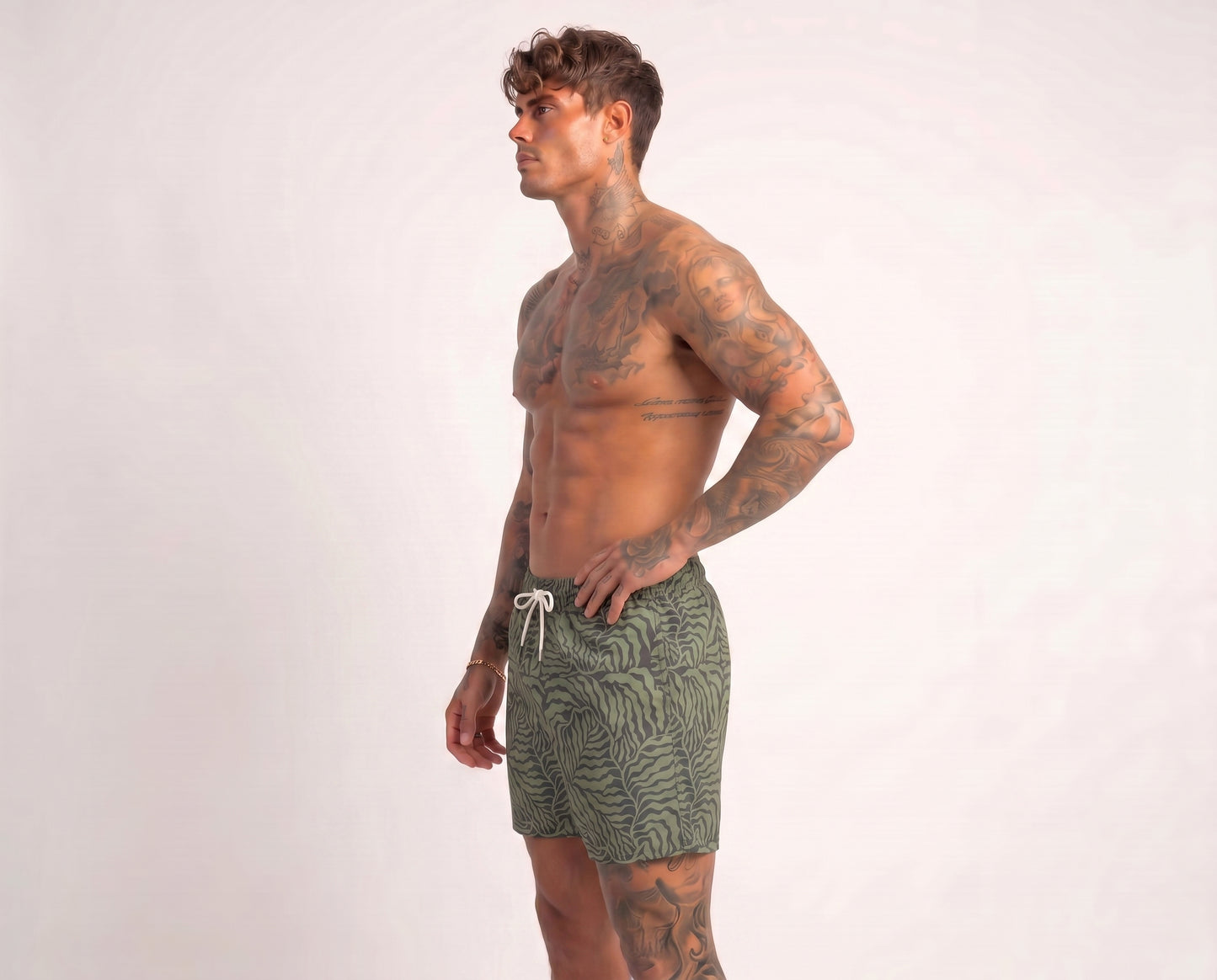 Man wearing green patterned swim shorts on a white background