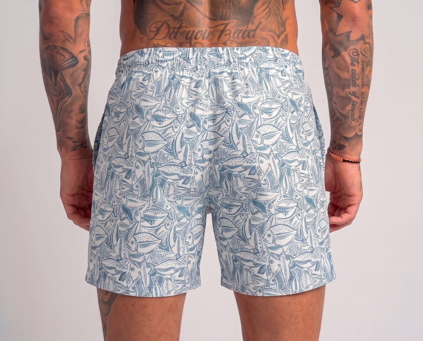 Person wearing blue leaf-patterned shorts on a plain background