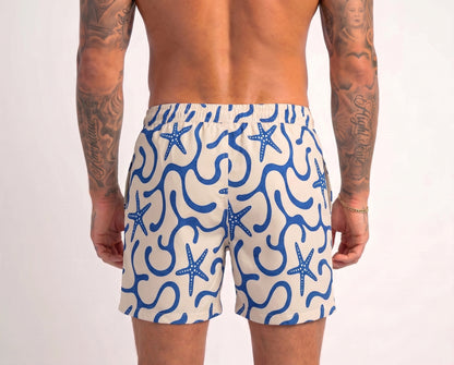 Person wearing blue and white patterned swim shorts with starfish design on a plain background