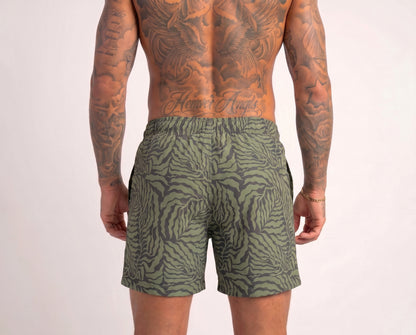 Person wearing green patterned shorts on a plain background